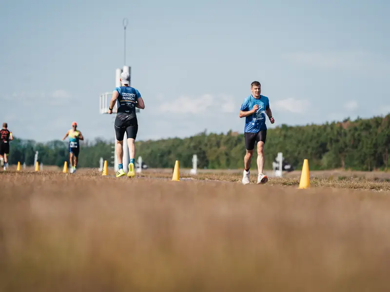 Dva běžci na travnaté běžecké trati v Labe aréně Račice